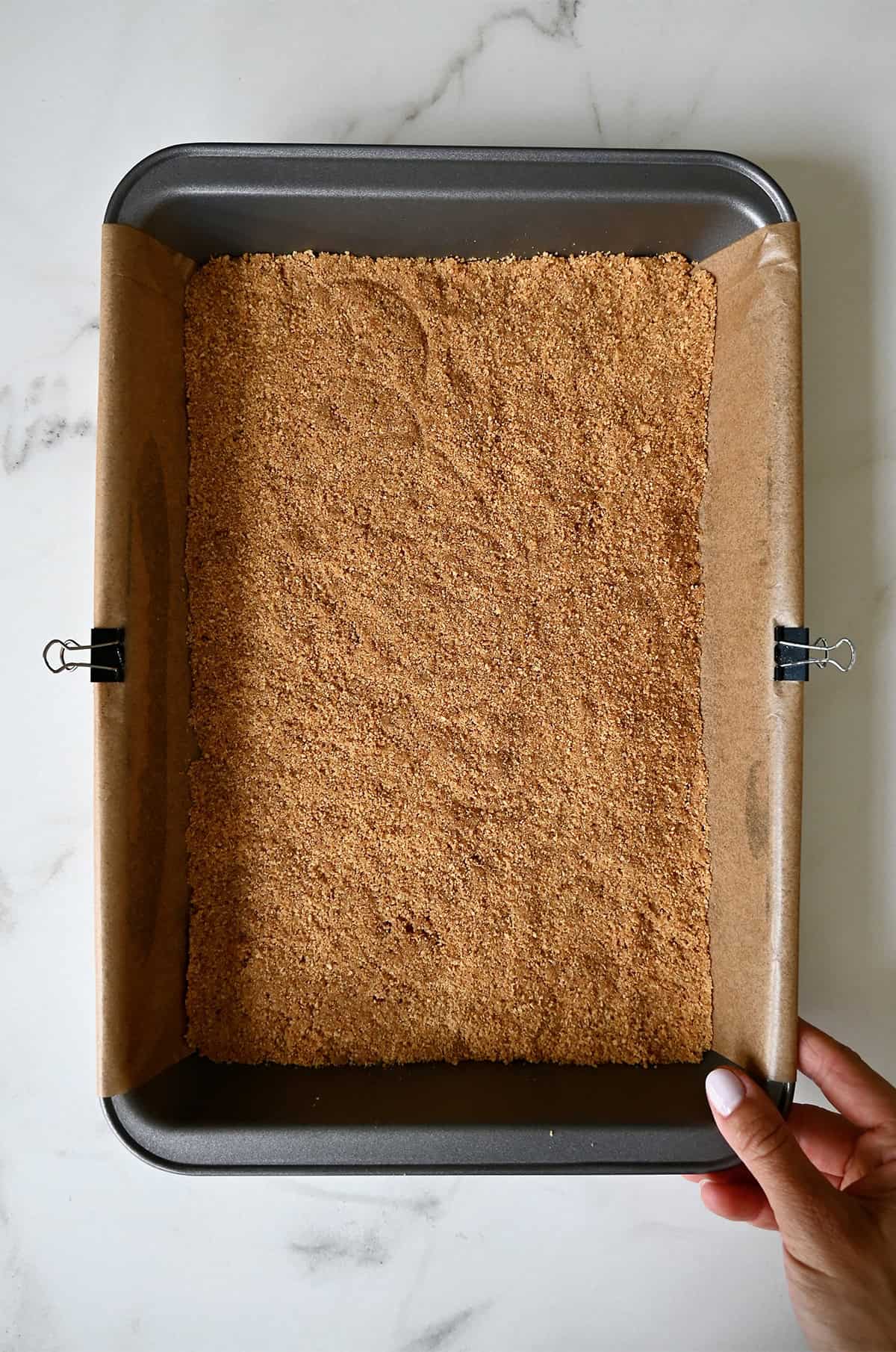 A graham cracker crust in a parchment paper-lined 9x13 baking pan.