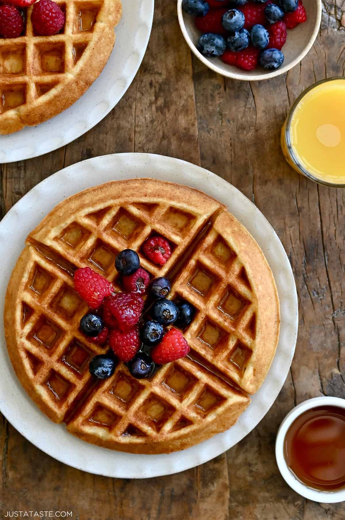 A perfeclty crisp, golden brown protein waffle topped with maple syrup and fresh berries on a large plate.