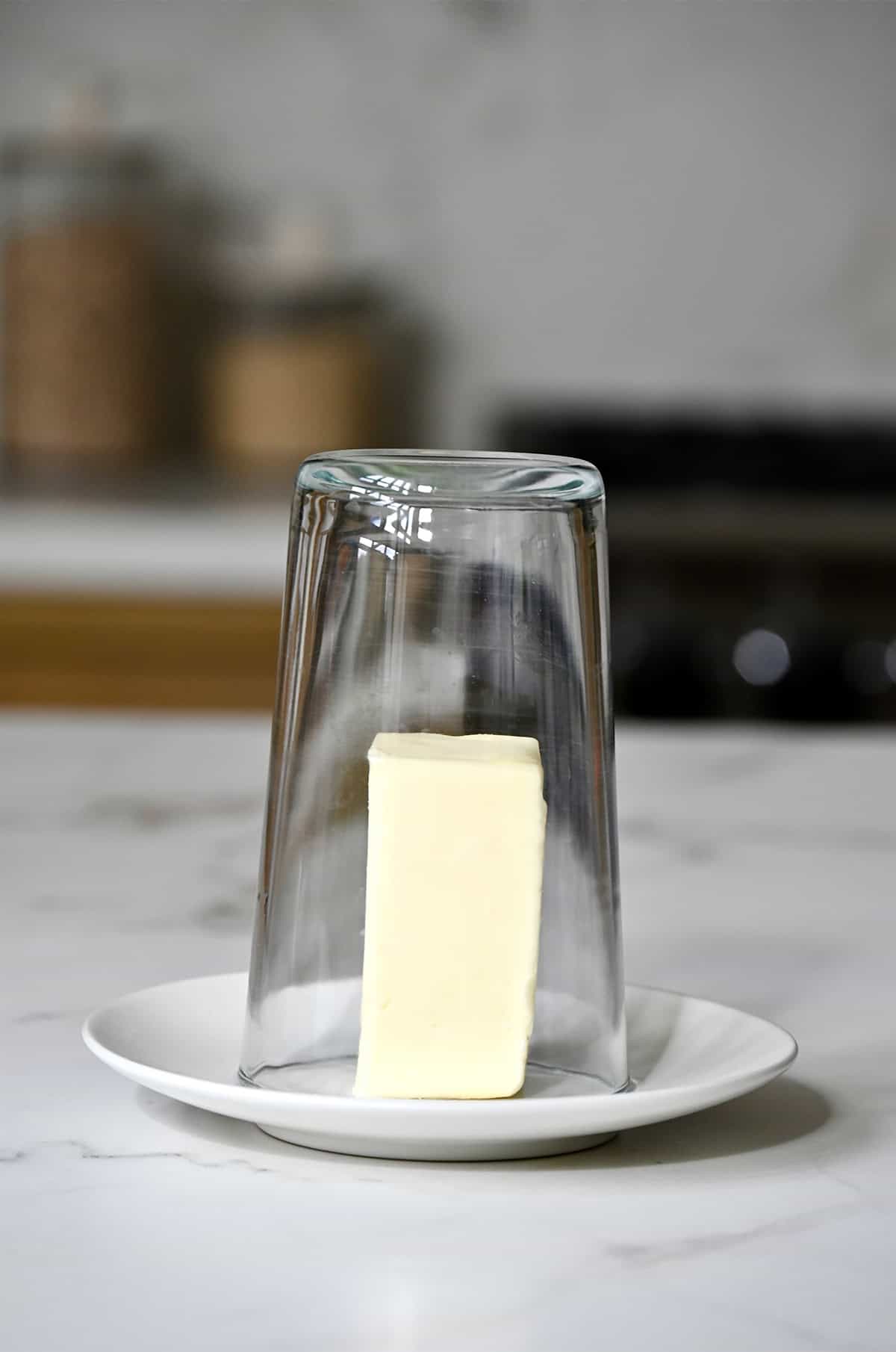 A hot glass is turned upside down over a stick of butter to soften it.
