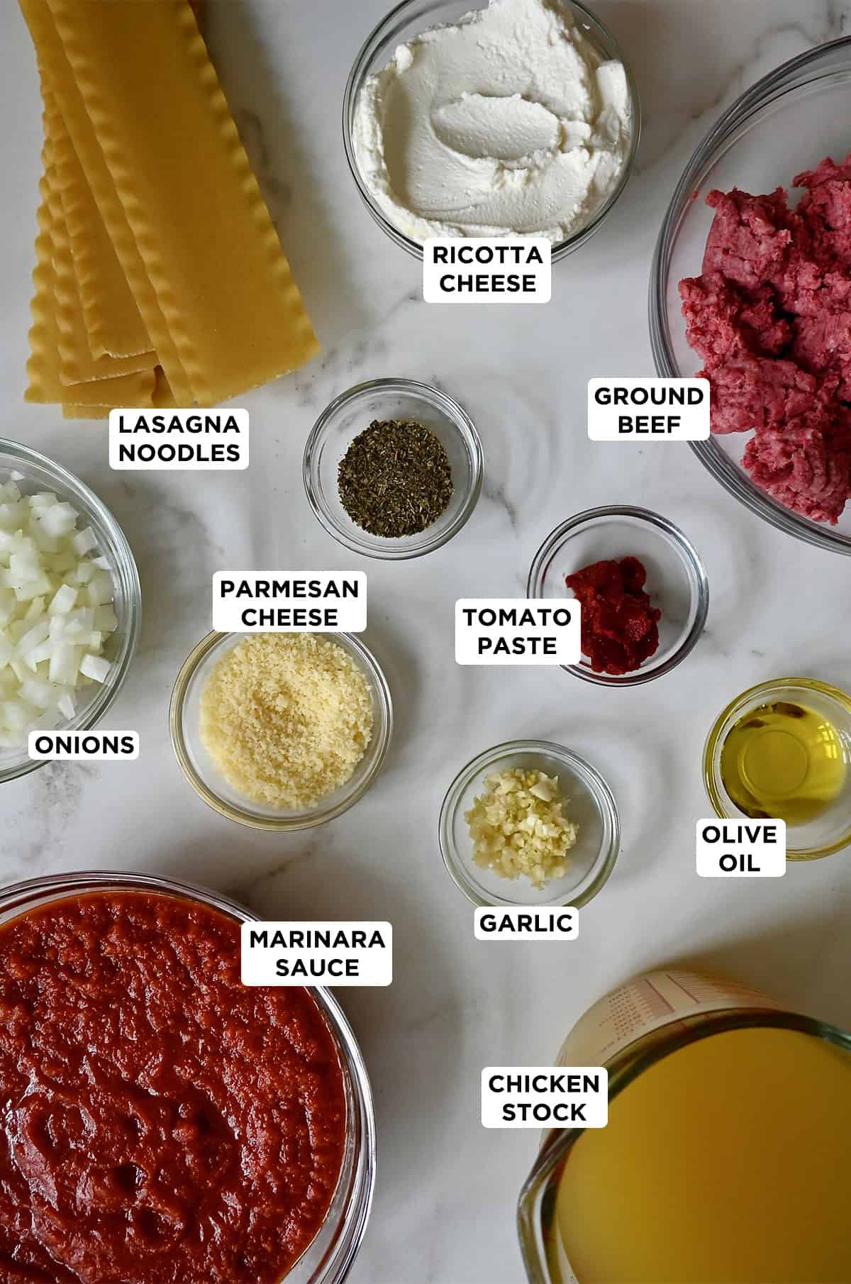 Various sizes of glass bowls containing all of the ingredients needed to make lasagna soup.
