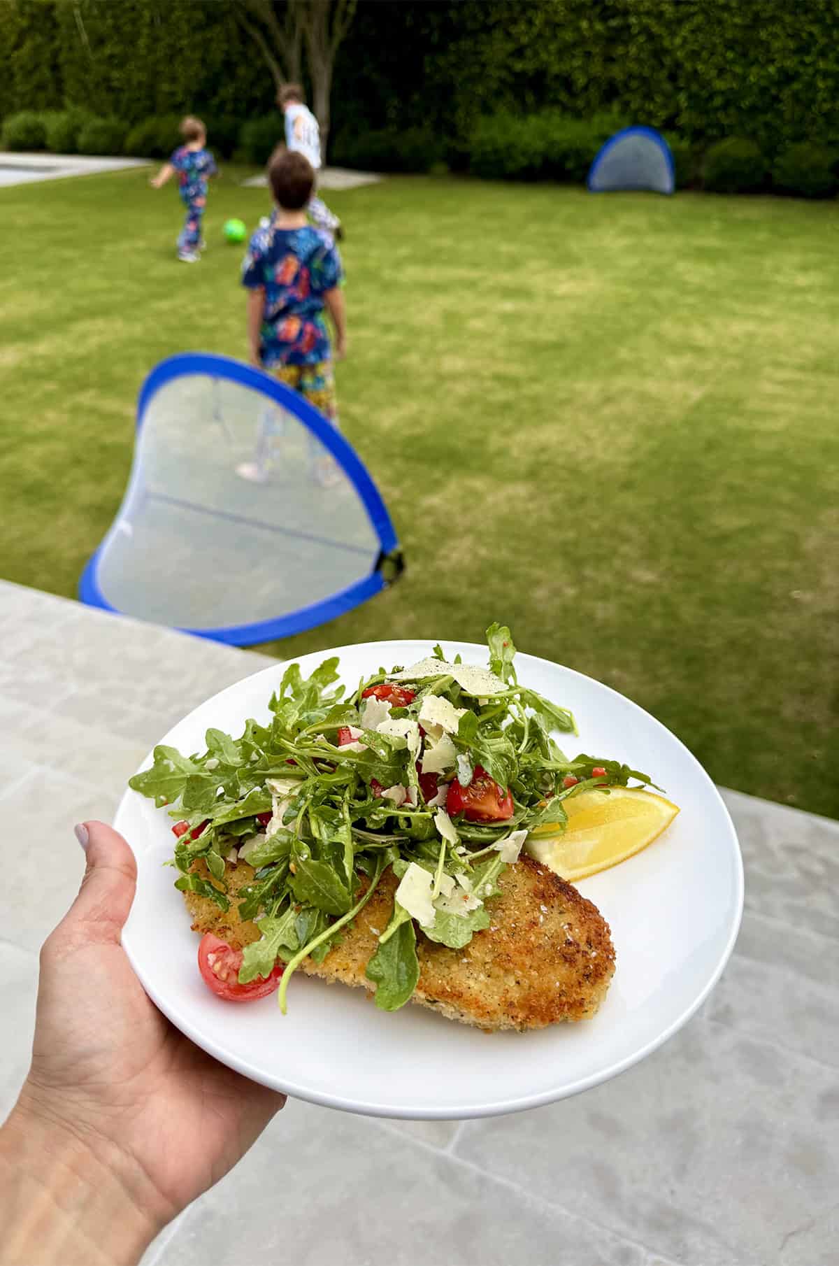 Chicken Cutlets on a plate with arugula salad with a soccer field in the background