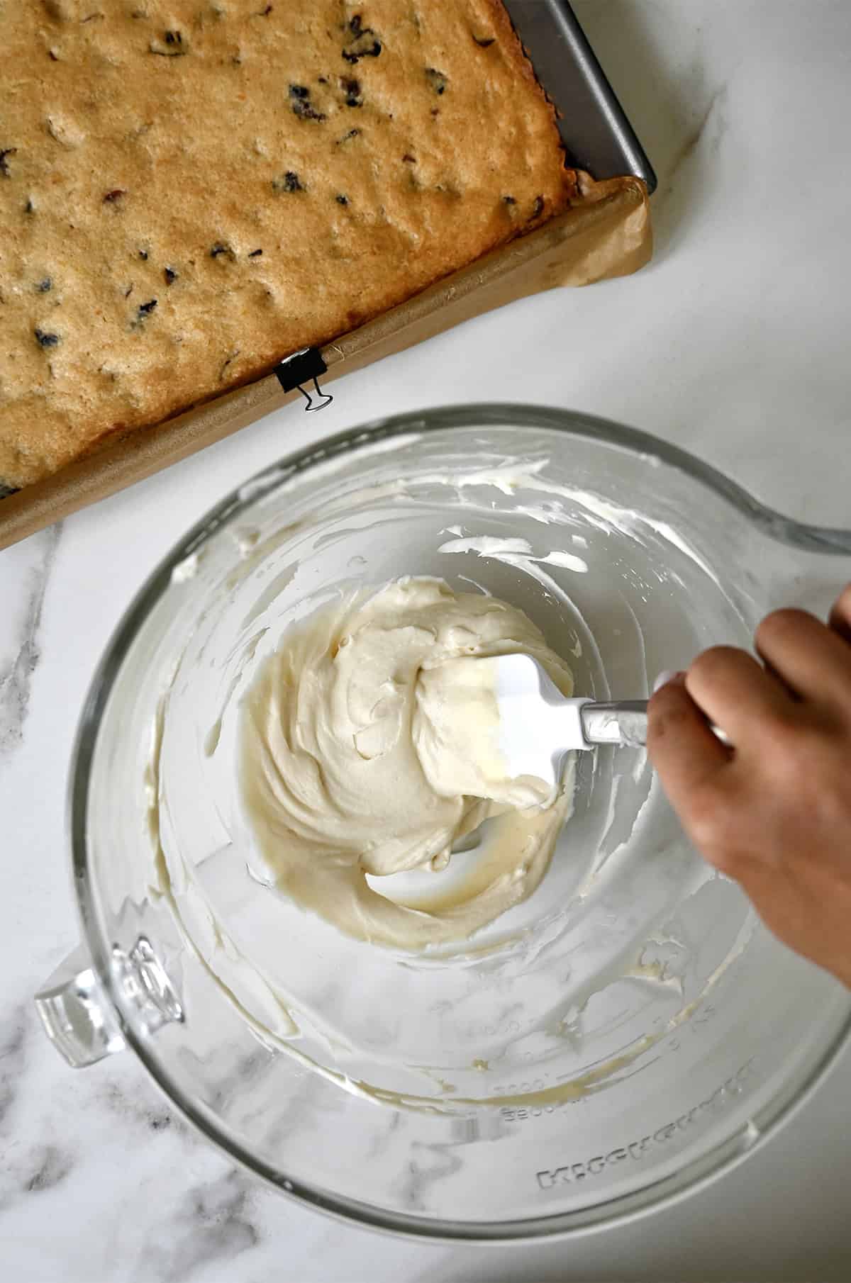 Tangy cream cheese frosting for cranberry bliss bars in a glass bowl.