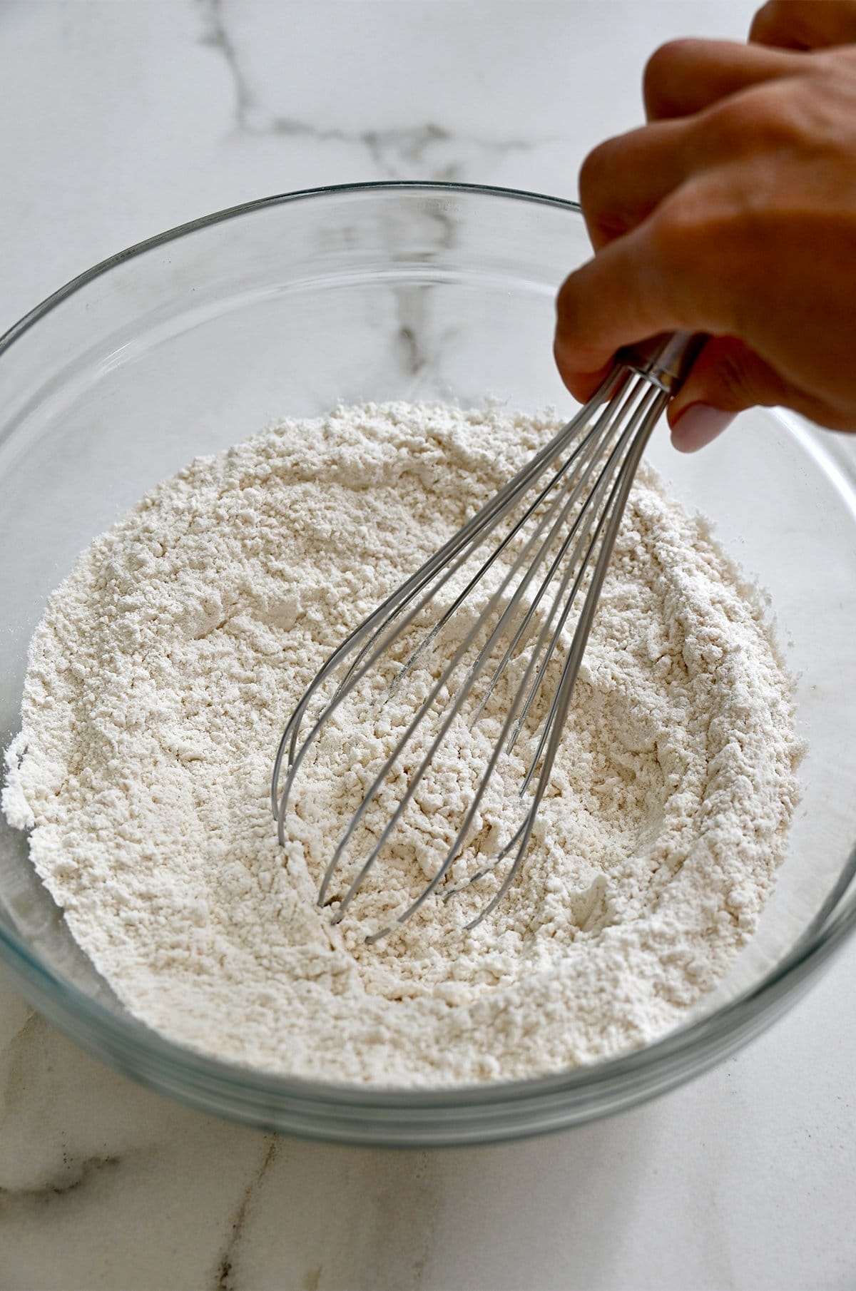 Whisking dry ingredients in a bowl for waffle batter.