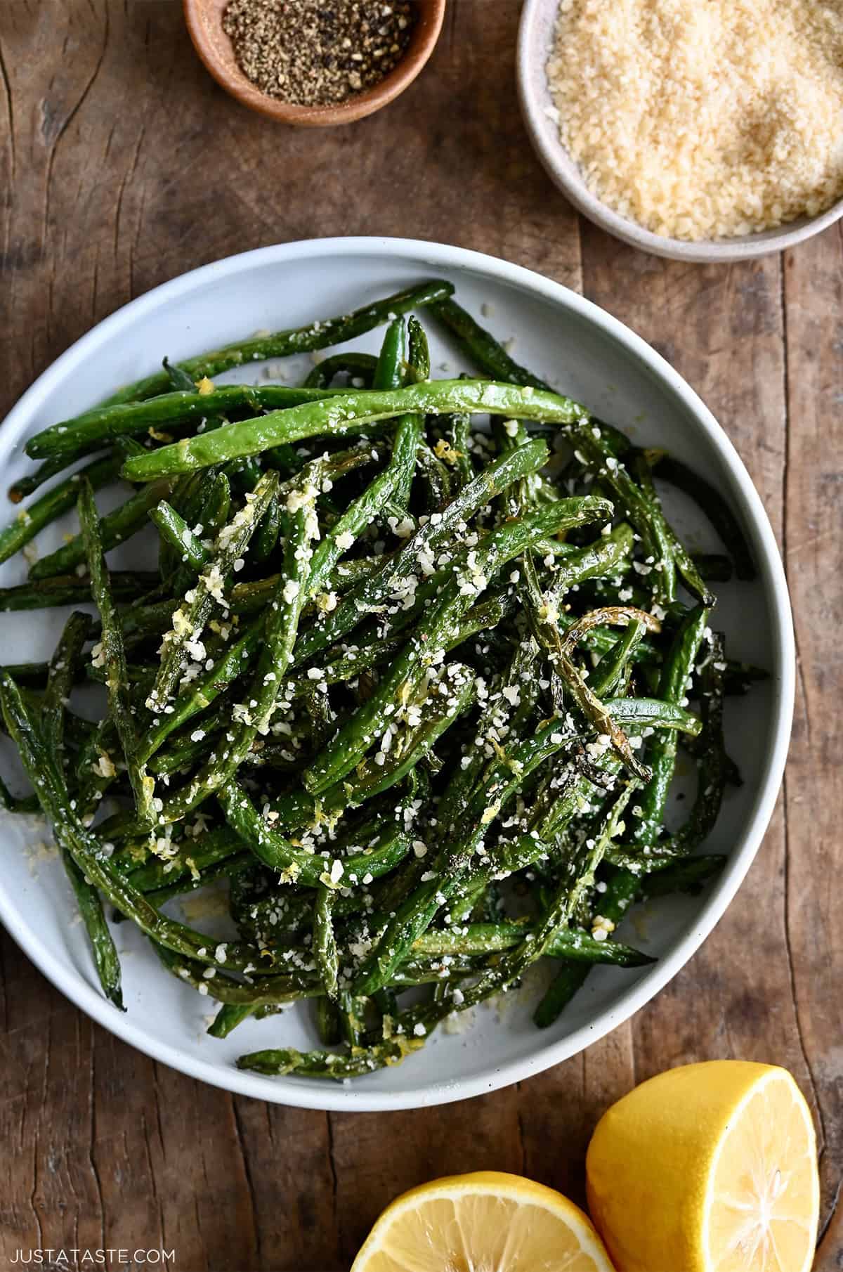 Roasted green beans with lemon juice, lemon zest and freshly grated Parmesan cheese in a serving bowl.