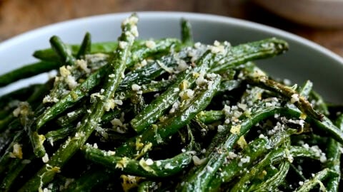 Roasted green beans with grated Parmesan in a serving bowl.