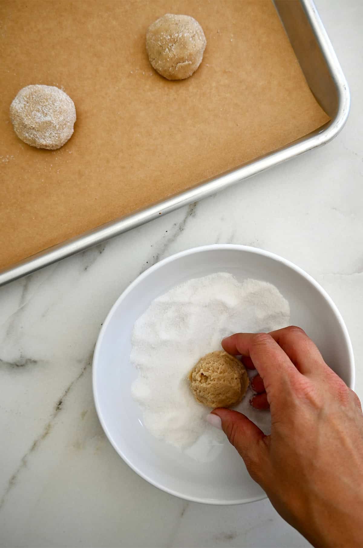 Rolling chai cookie dough balls in sugar before baking.