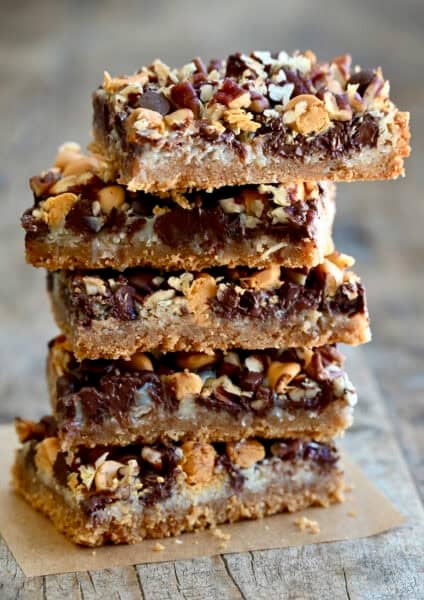 Magic cookie bars stacked five high on a piece of parchment paper.