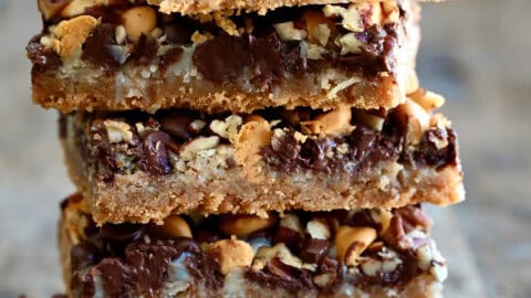 Magic cookie bars stacked five high on a piece of parchment paper.