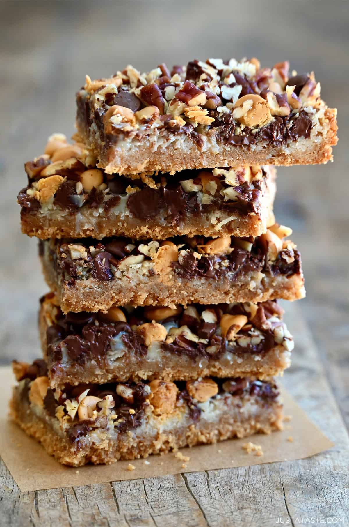 Magic cookie bars stacked five high on a piece of parchment paper.