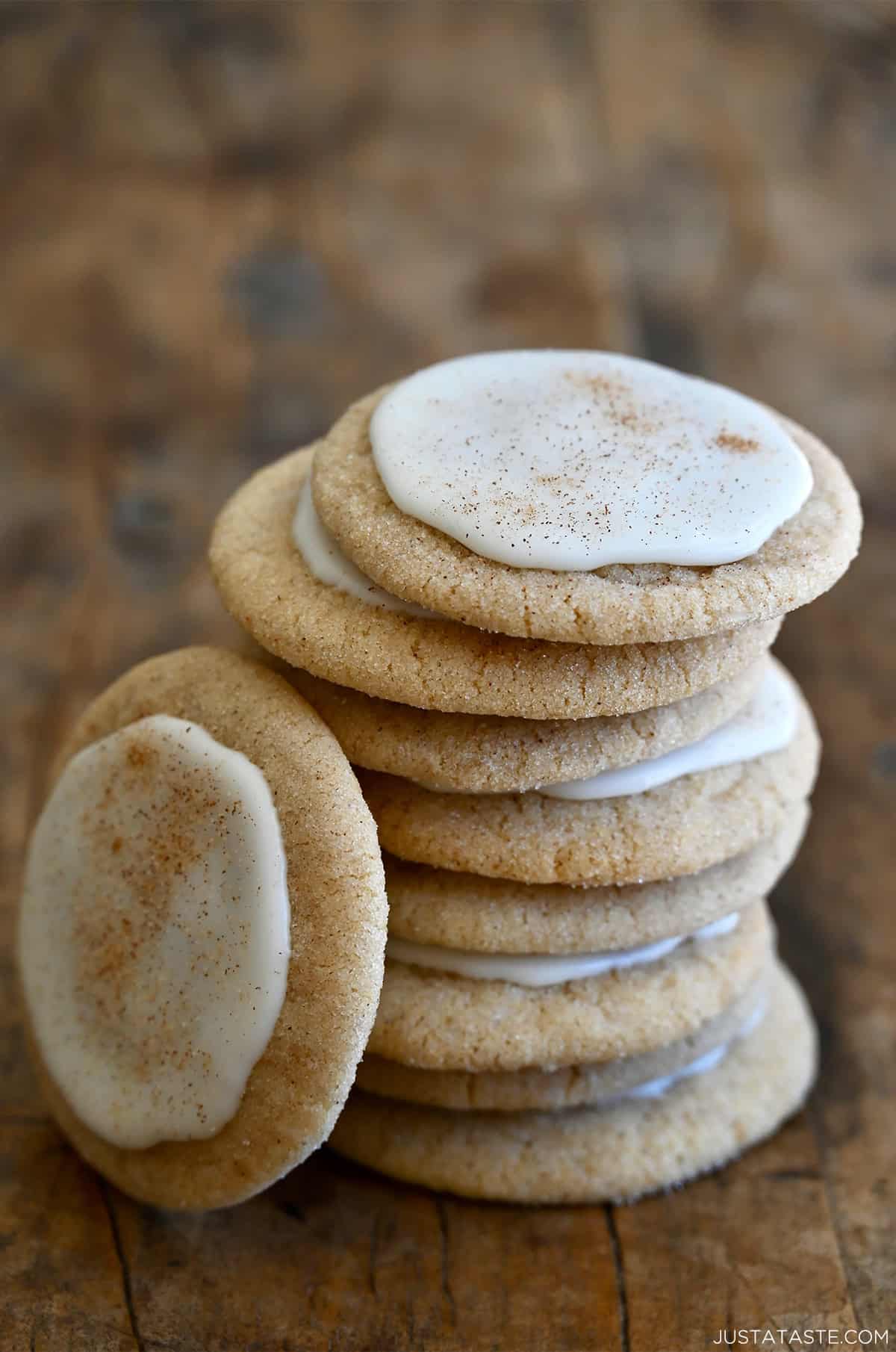 Chai sugar cookies with a cinnamon icing stacked eight high, with another leaning up against them. 