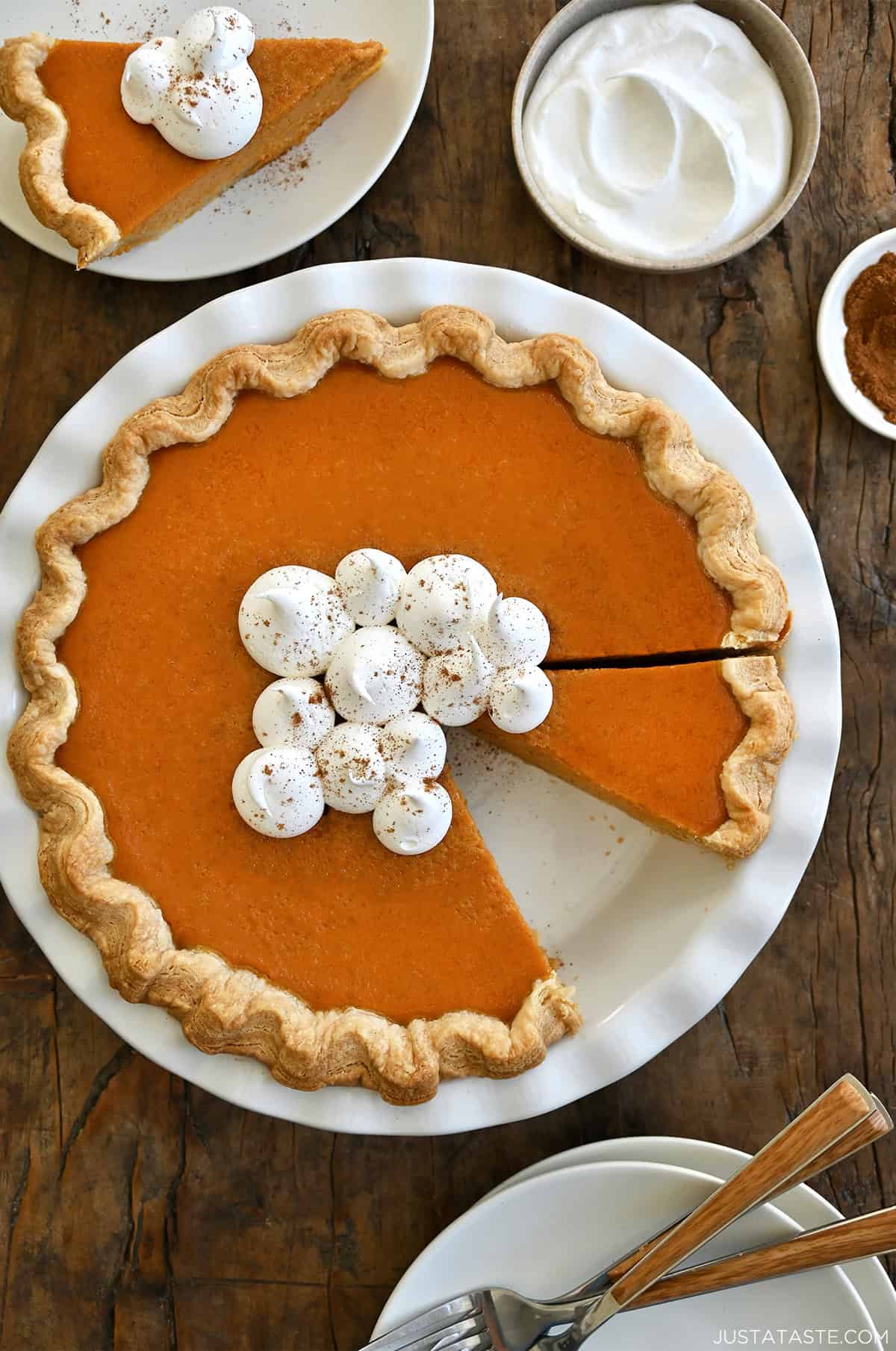 The best pumpkin pie from scratch with homemade pie crust topped with dollops of whipped cream and sprinkled with a dash of pumpkin pie spice.