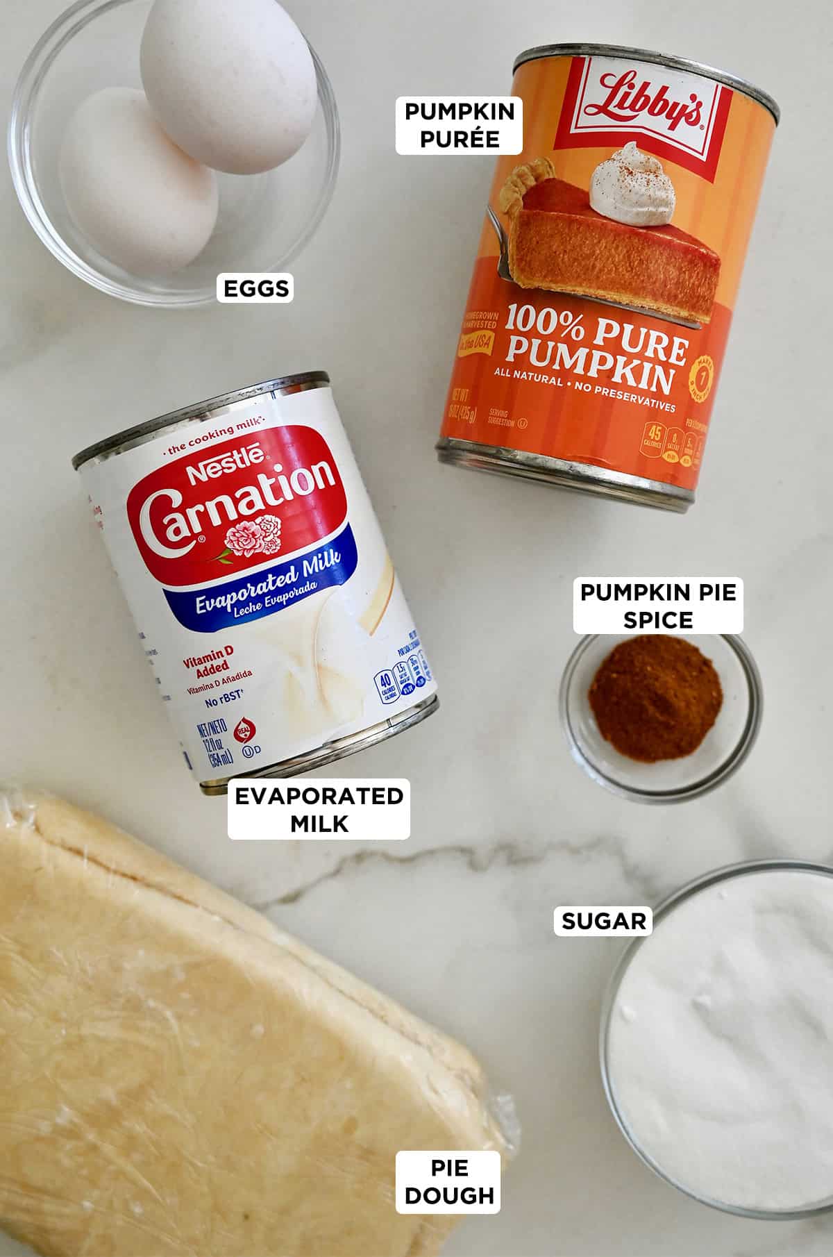 Ingredients to make pumpkin pie: pumpkin purée, evaporated milk, pumpkin pie spice, sugar, eggs and pie crust.