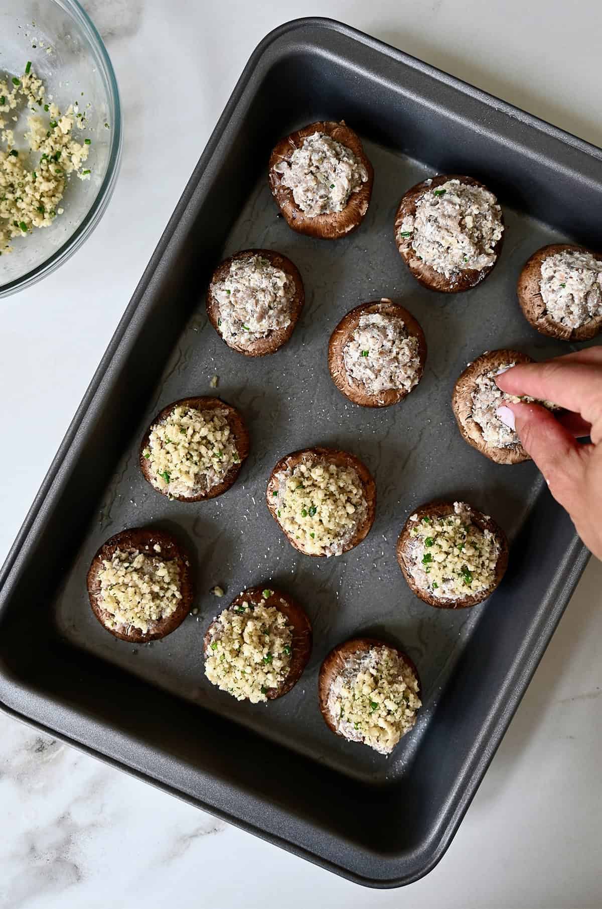 Stuffed mushrooms in a baking dish with Panko topping before baking.