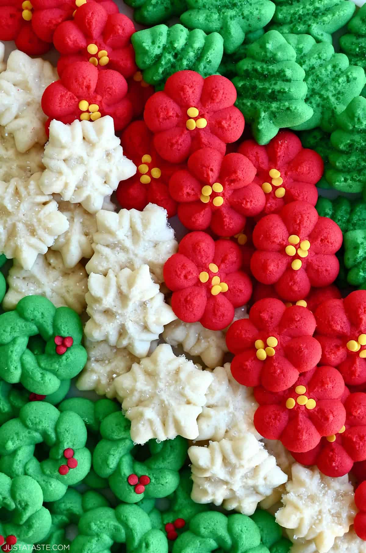 Red and green spritz cookies, along with snowflake-shaped spritz cookies, on a plate.