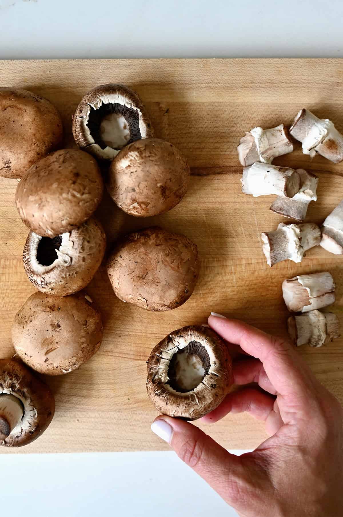Cleaning and removing the stems from mushrooms to prep them for stuffing.
