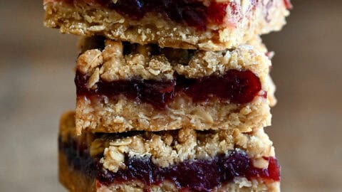 Four cranberry crumble bars stacked atop each other.