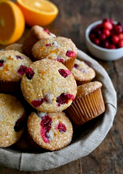 Cranberry orange muffins with a crunchy sanding sugar topping in a lined bread basket.