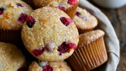 Cranberry orange muffins with a crunchy sanding sugar topping in a lined bread basket.