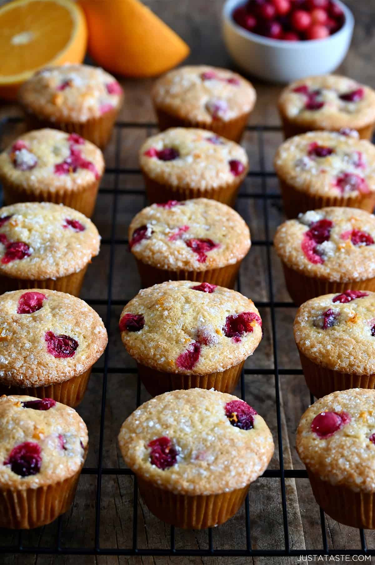 Three rows of cranberry orange muffins cooling on a wire rack.