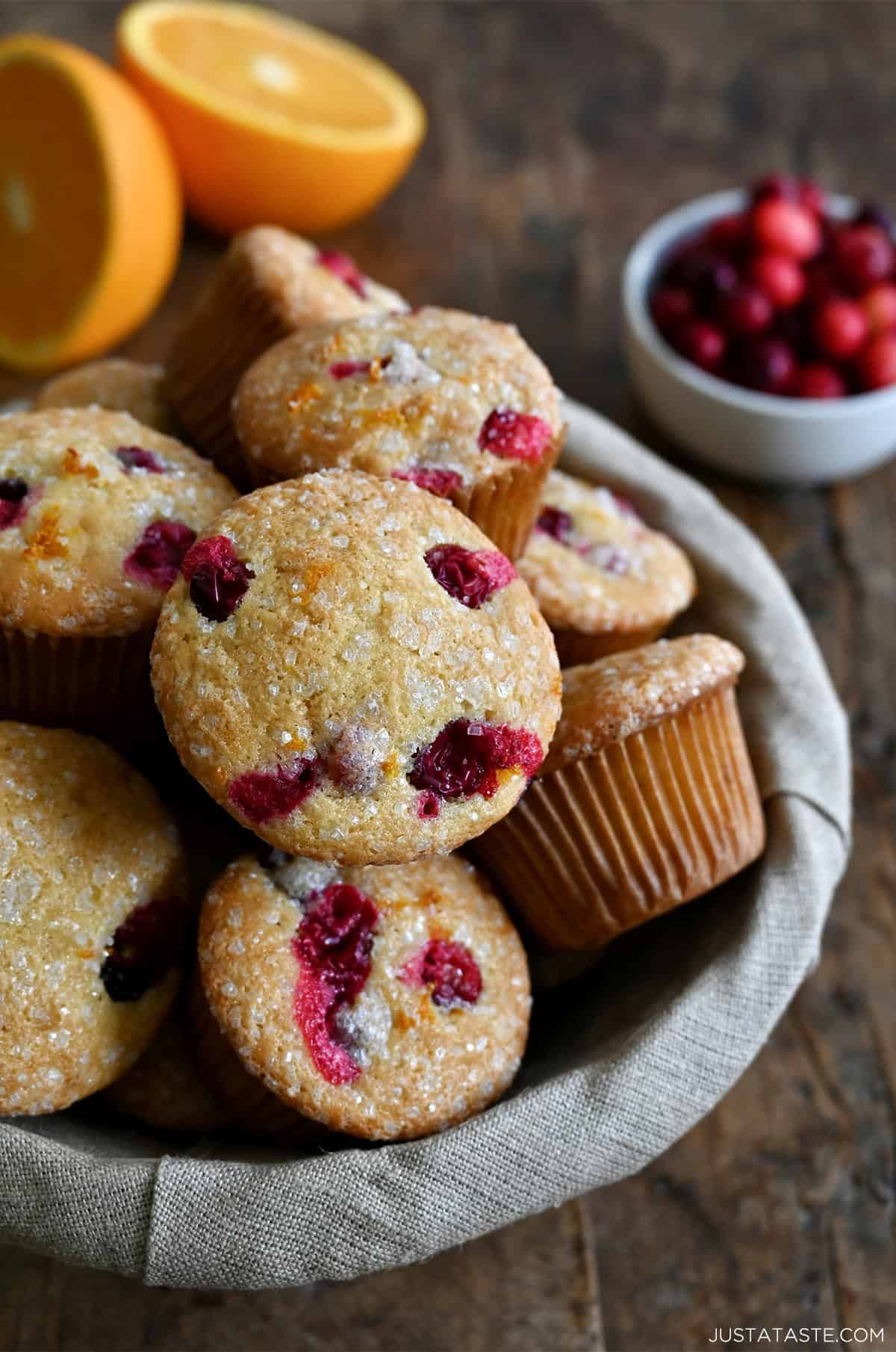 Cranberry orange muffins with a crunchy sanding sugar topping in a lined bread basket.