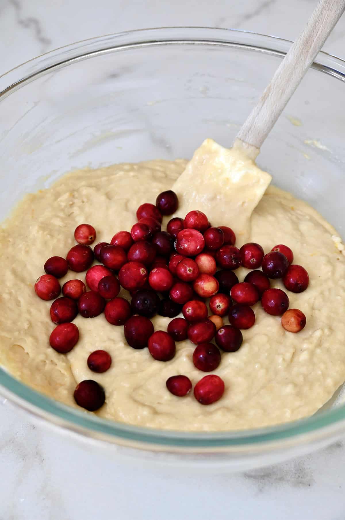 Folding fresh cranberries into an orange muffin batter.
