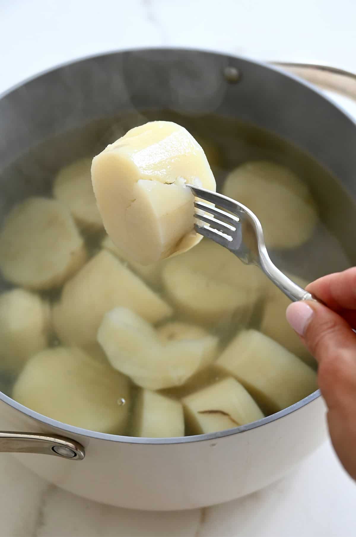 A fork pierces a boiled potato to show that it is fork-tender.
