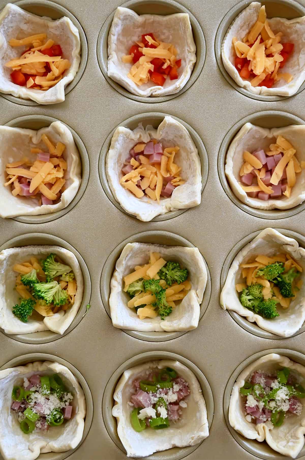 Sluoksniuotos tešlos puodeliai, užpildyti įvairiais kišų įdarais, įskaitant kubeliais pjaustytą kumpį ir sūrį, kapotus brokolius ir sūrį bei kubeliais pjaustytą raudonąją papriką su susmulkintu čederiu.