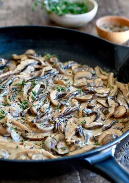 Creamy mushroom sauce garnished with thyme in a large skillet.