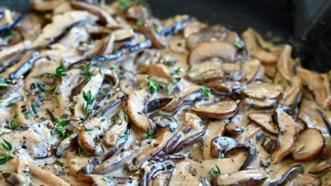 Creamy mushroom sauce garnished with thyme in a large skillet.
