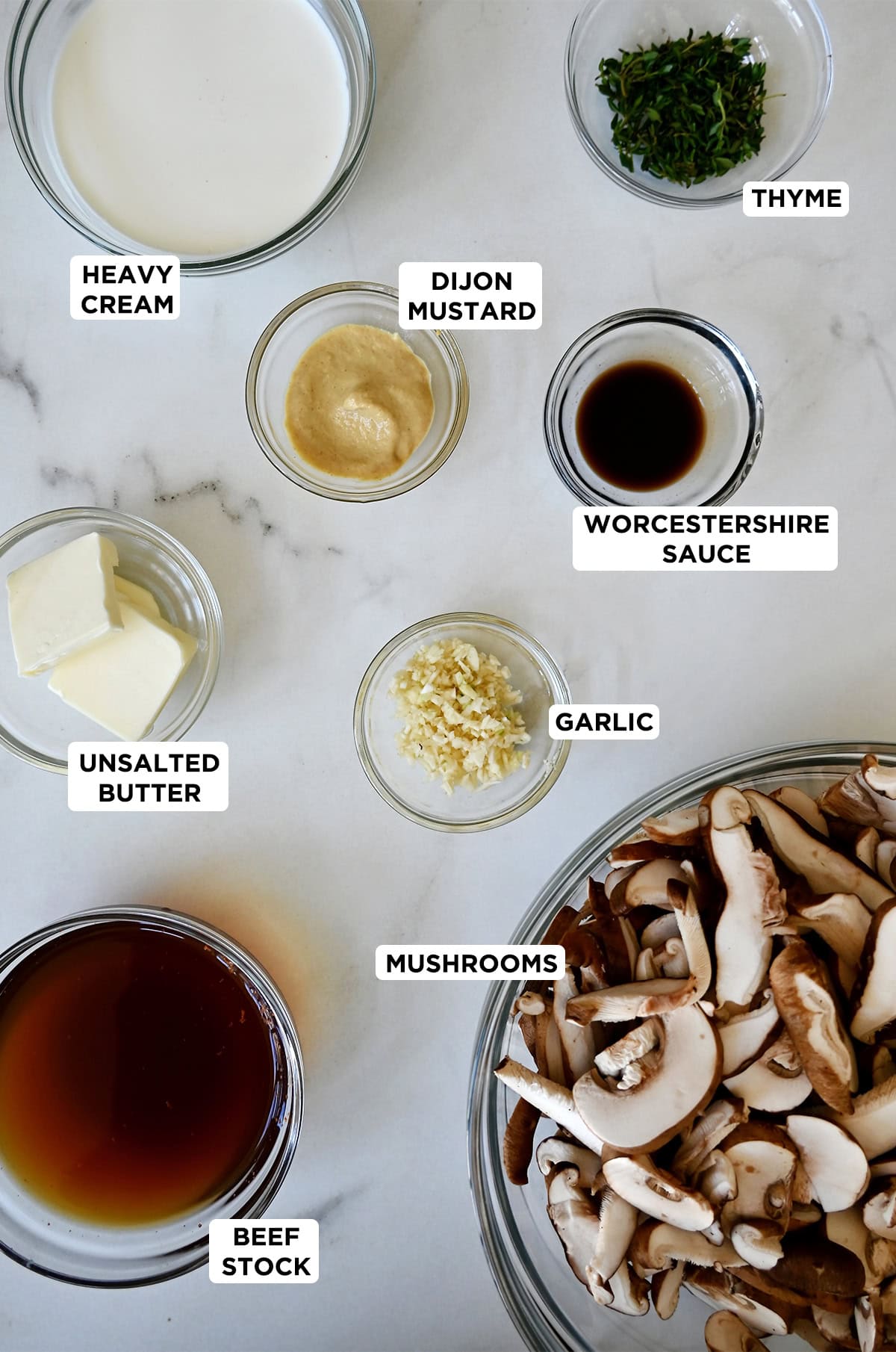 Ingredients to make creamy mushroom sauce for steak, chicken, pork and more, in various sizes of glass bowls.