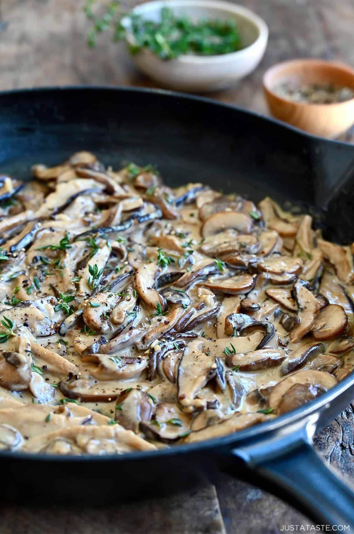 Creamy mushroom sauce garnished with thyme in a large skillet.