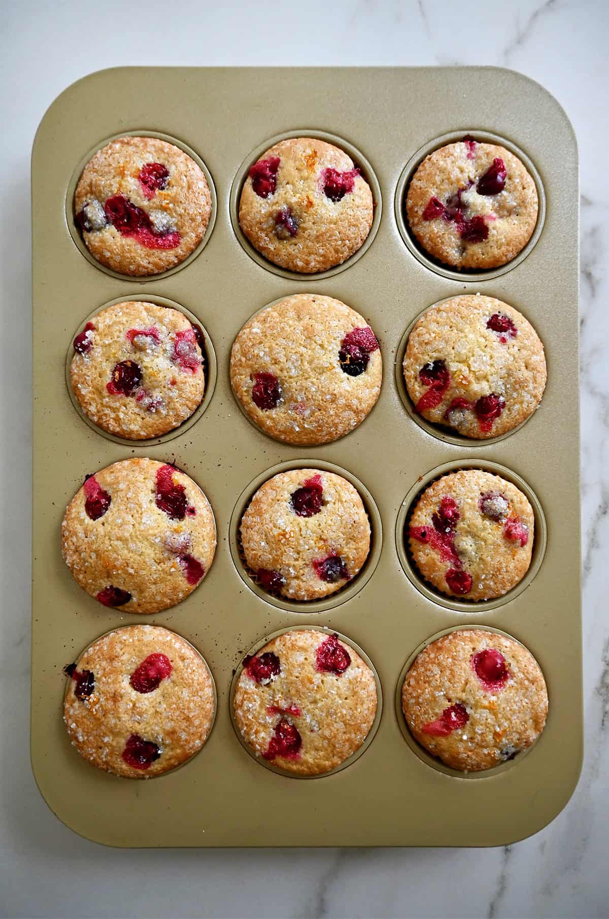 Freshly baked cranberry orange muffins in a standard muffin tin.