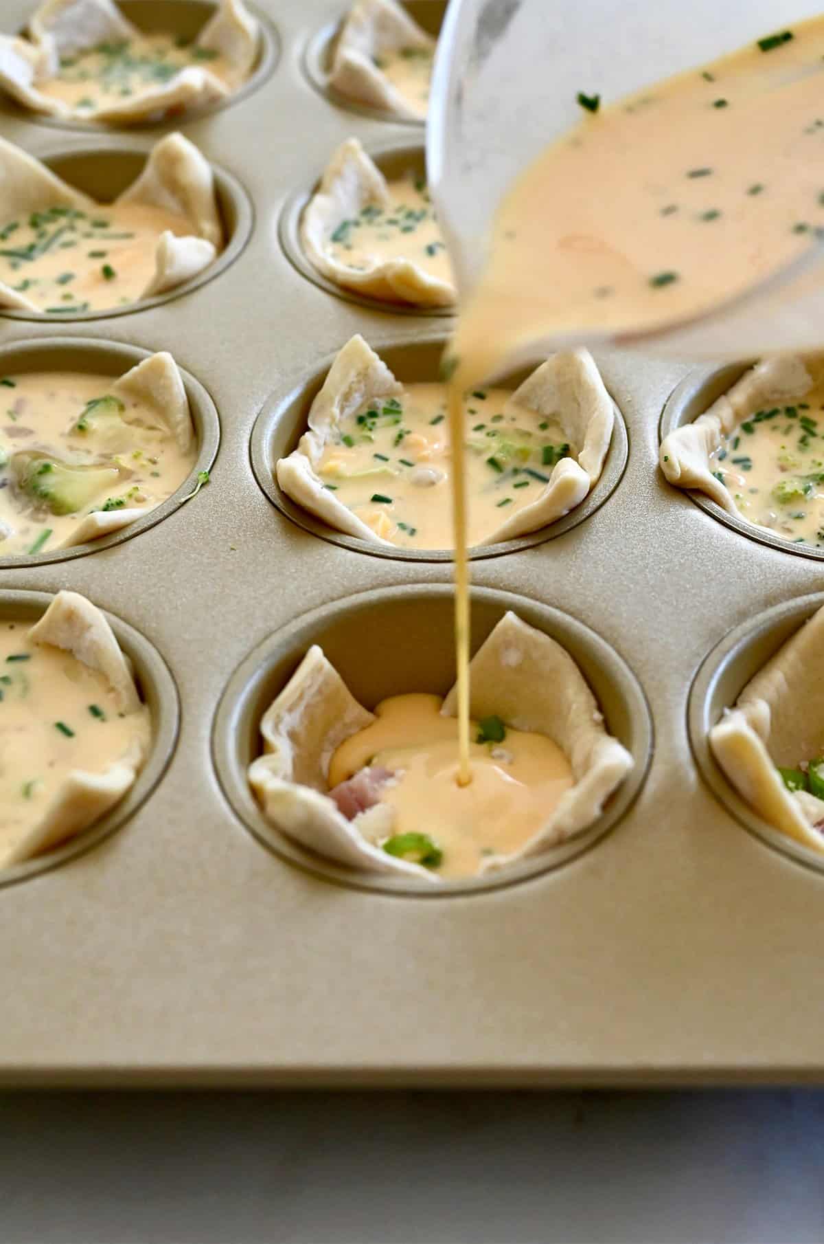 Supilkite išplaktus kiaušinius į sluoksniuotos tešlos puodelius bandelių formoje, kad pagamintumėte mini kišelius.