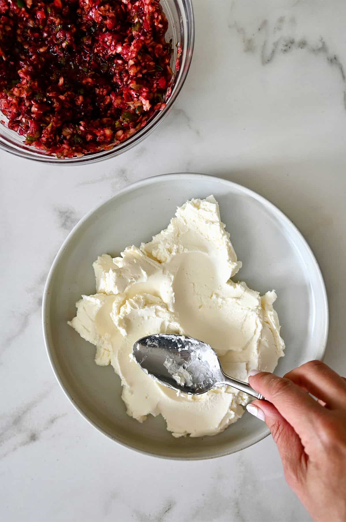 Spreading softened cream cheese with the back of a spoon onto a serving plate.