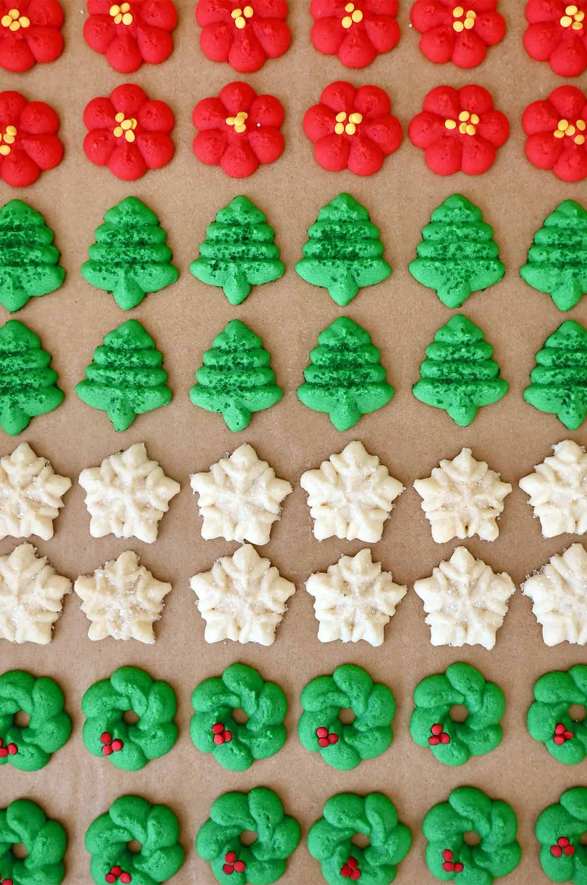 Festive holiday spritz cookies with sanding sugar on a cookie sheet.