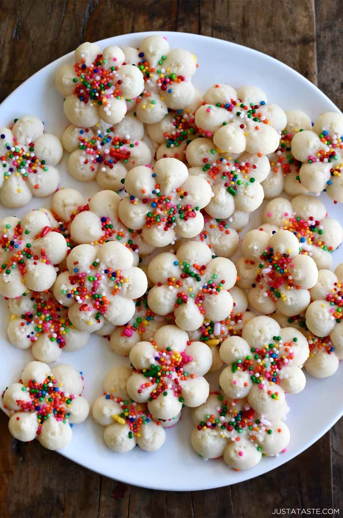 Buttery spritz cookies with rainbow sprinkles on a plate.