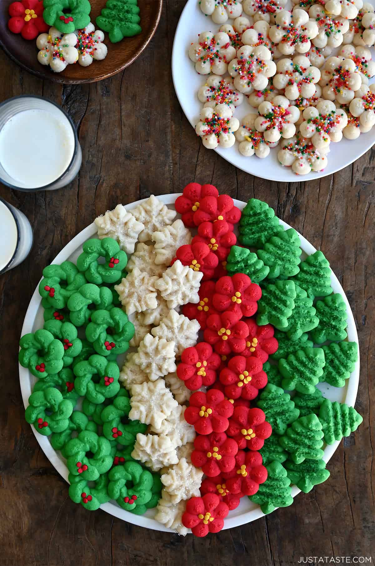 A cookie tray with a variety of traditional spritz cookies, including green Christmas trees, red rosettes, snowflakes with sprinkles, and green wreaths.