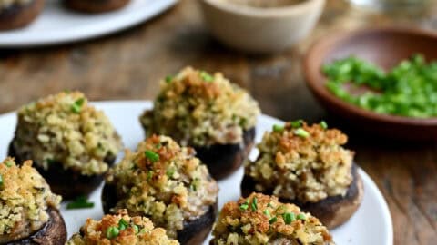 Sausage stuffed mushrooms on a white appetizer plate.