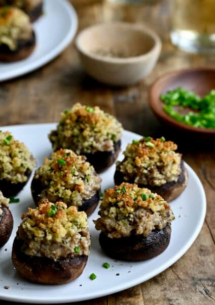 Homemade sausage stuffed mushrooms on a white appetizer plate, showing their cheesy filling and buttery Panko breadcrumb crust.
