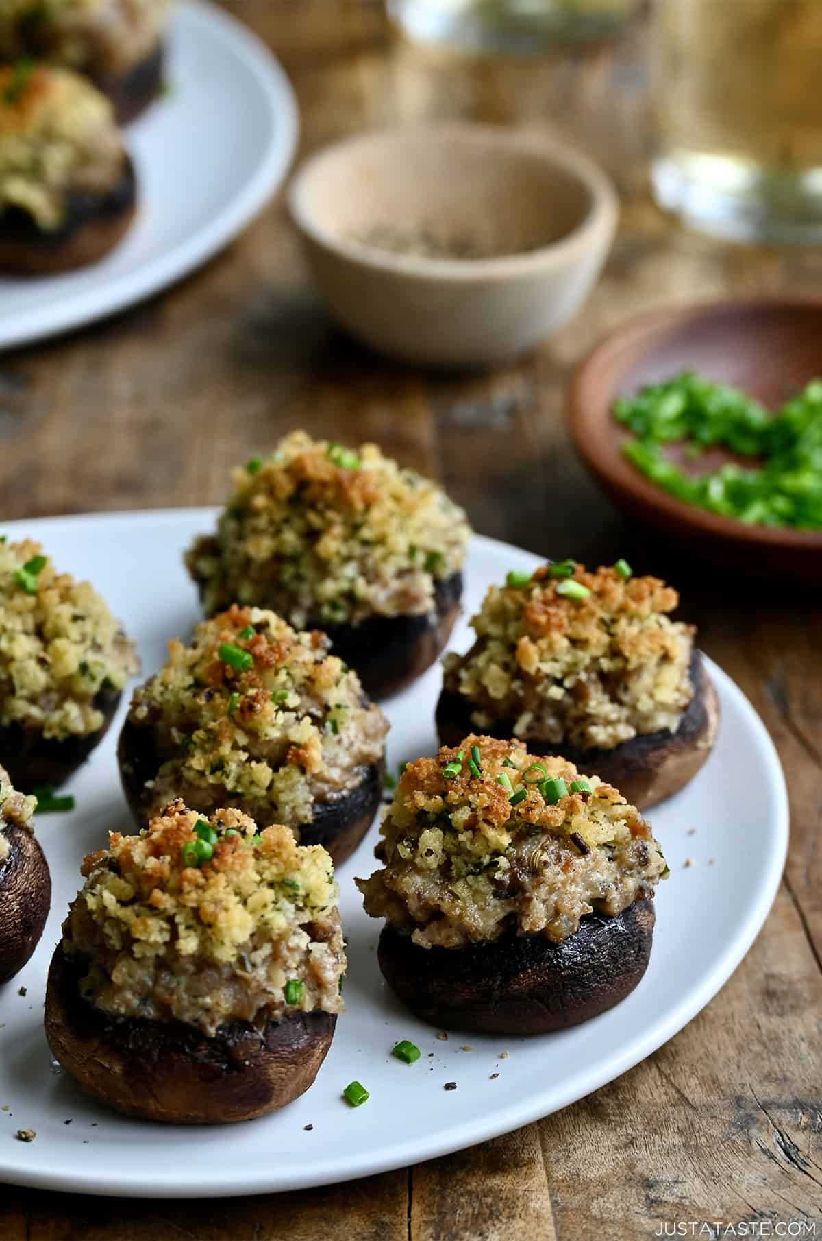 Homemade sausage stuffed mushrooms on a white appetizer plate, showing their cheesy filling and buttery Panko breadcrumb crust.
