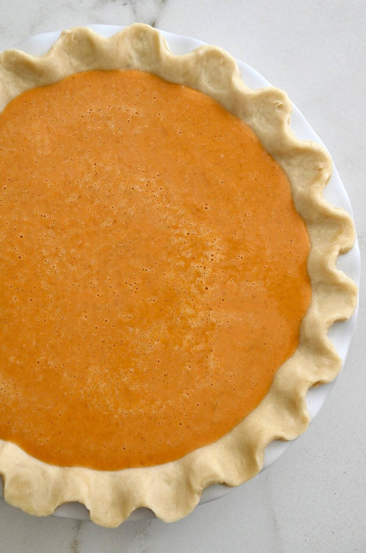 Unbaked pumpkin pie in a deep dish pie pan before going into the oven.