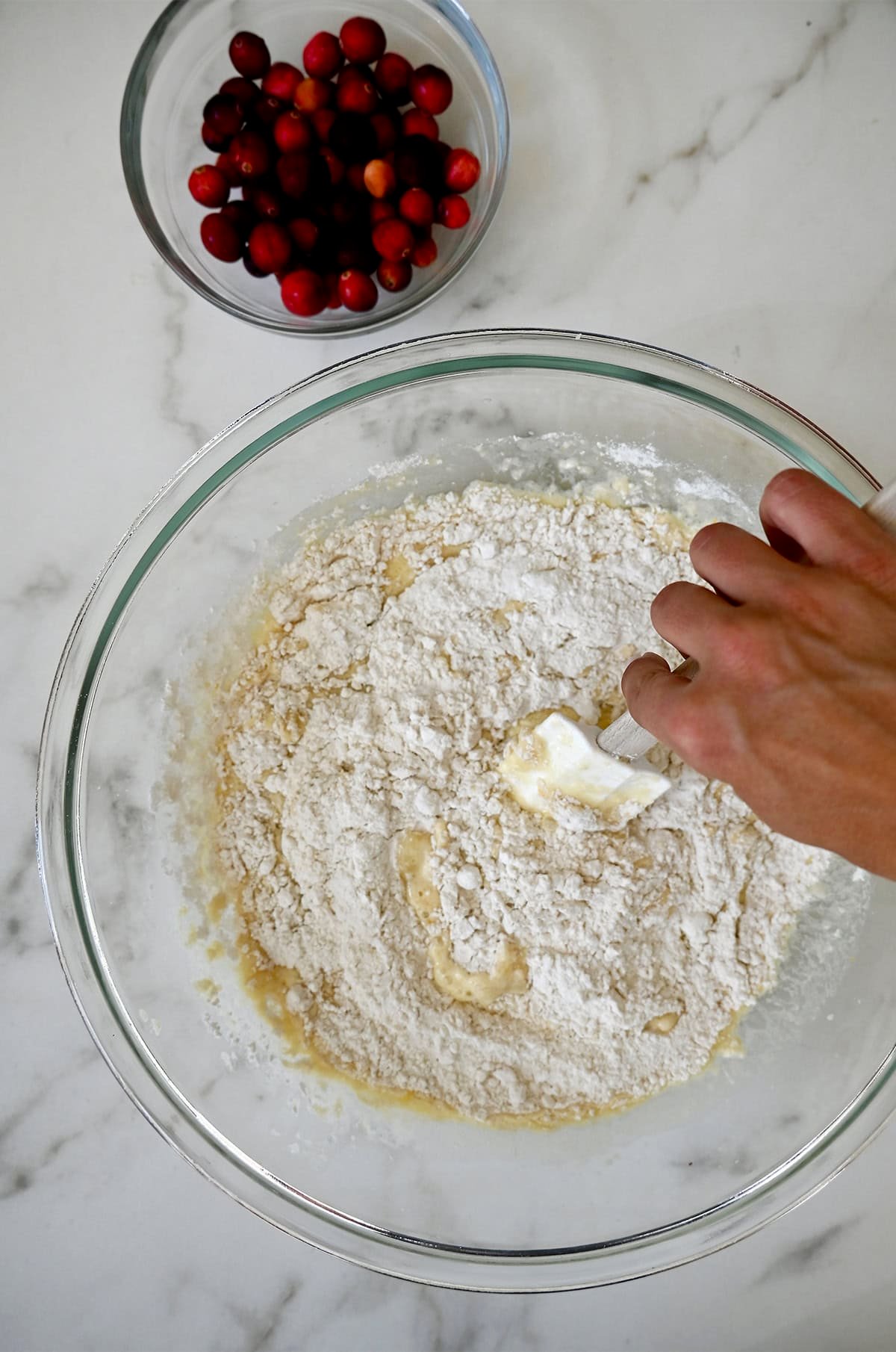 Stirring together wet and dry ingredients in a bowl for a citrusy muffin batter.