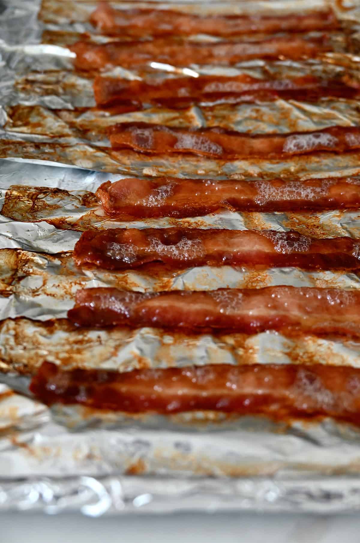 Crispy oven-baked bacon on an aluminum foil pan.