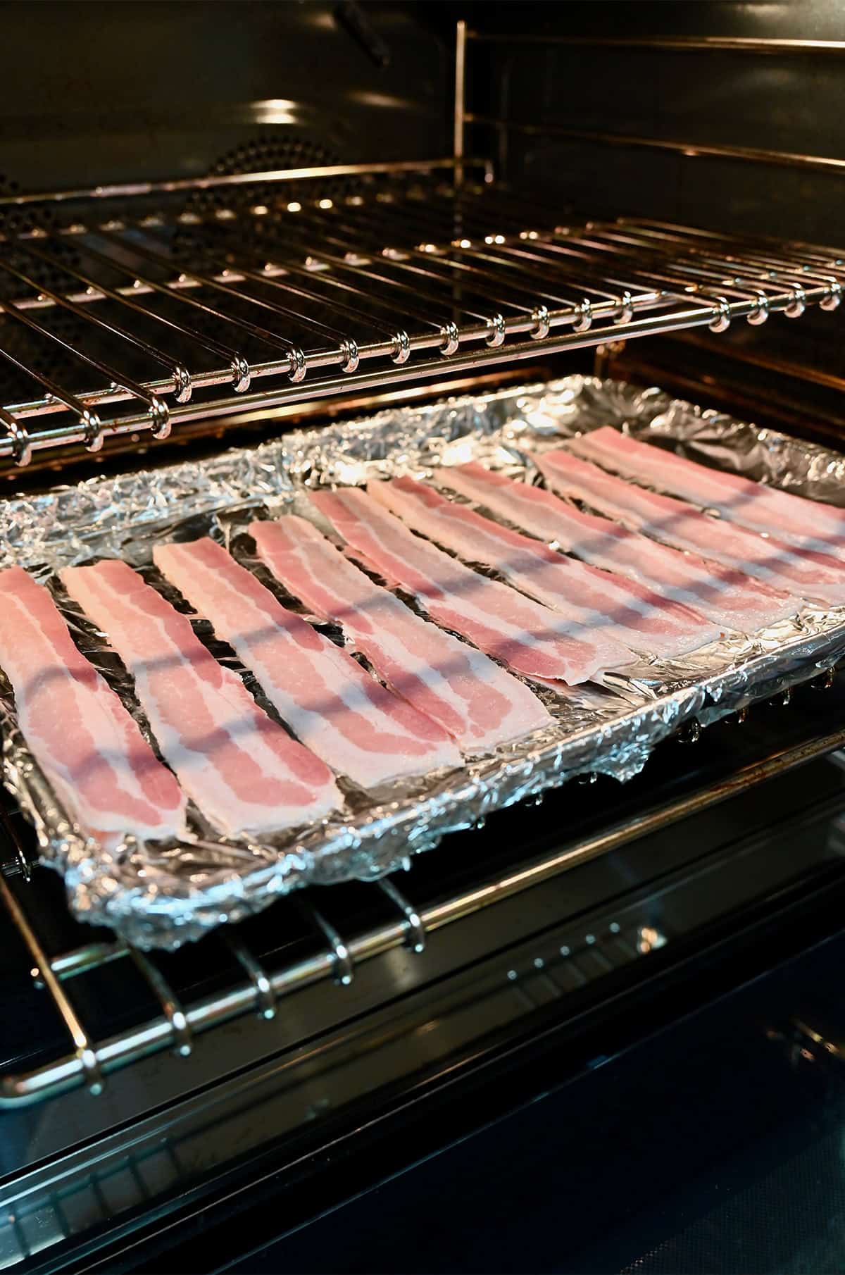 Cooking bacon in the oven on an aluminum foil-lined sheet pan.