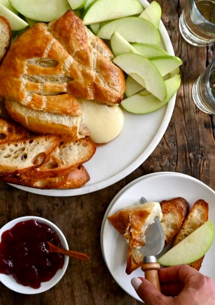 Golden baked brie wrapped in puff pastry, sliced open with melted brie oozing from the center.