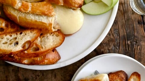 Golden baked brie wrapped in puff pastry, sliced open with melted brie oozing from the center.