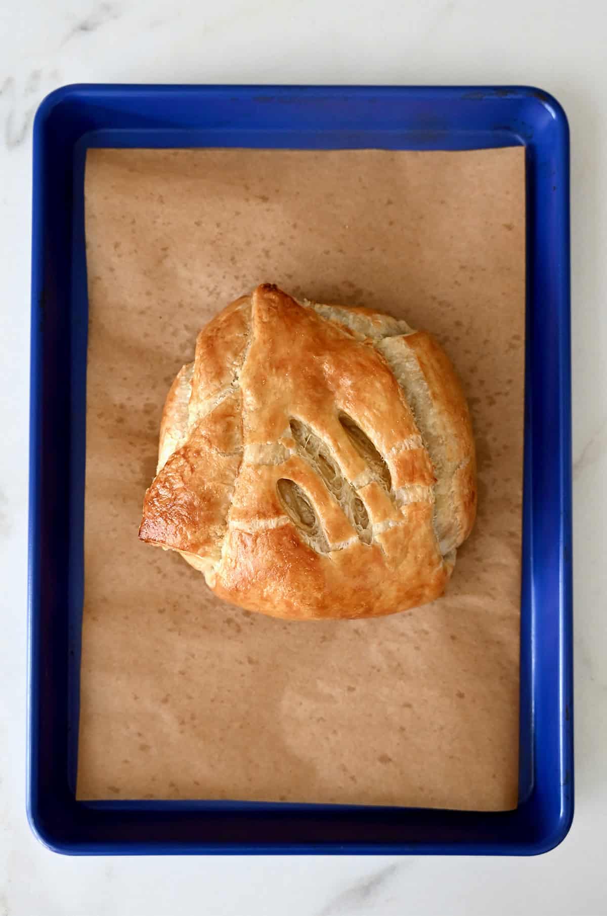 Baked Brie wrapped in golden brown puff pastry on a baking sheet.