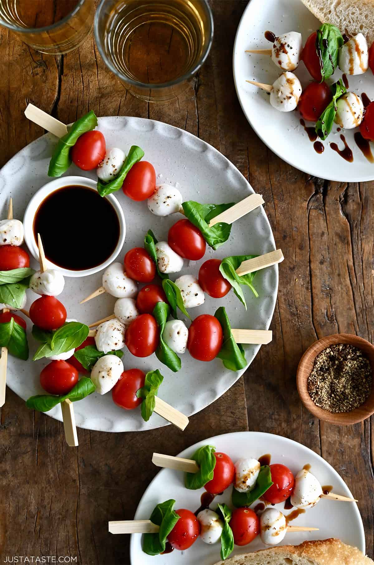 Caprese skewers arranged on a serving platter with cherry tomatoes, fresh mozzarella balls, and basil leaves, and sprinkled with flaky sea salt.