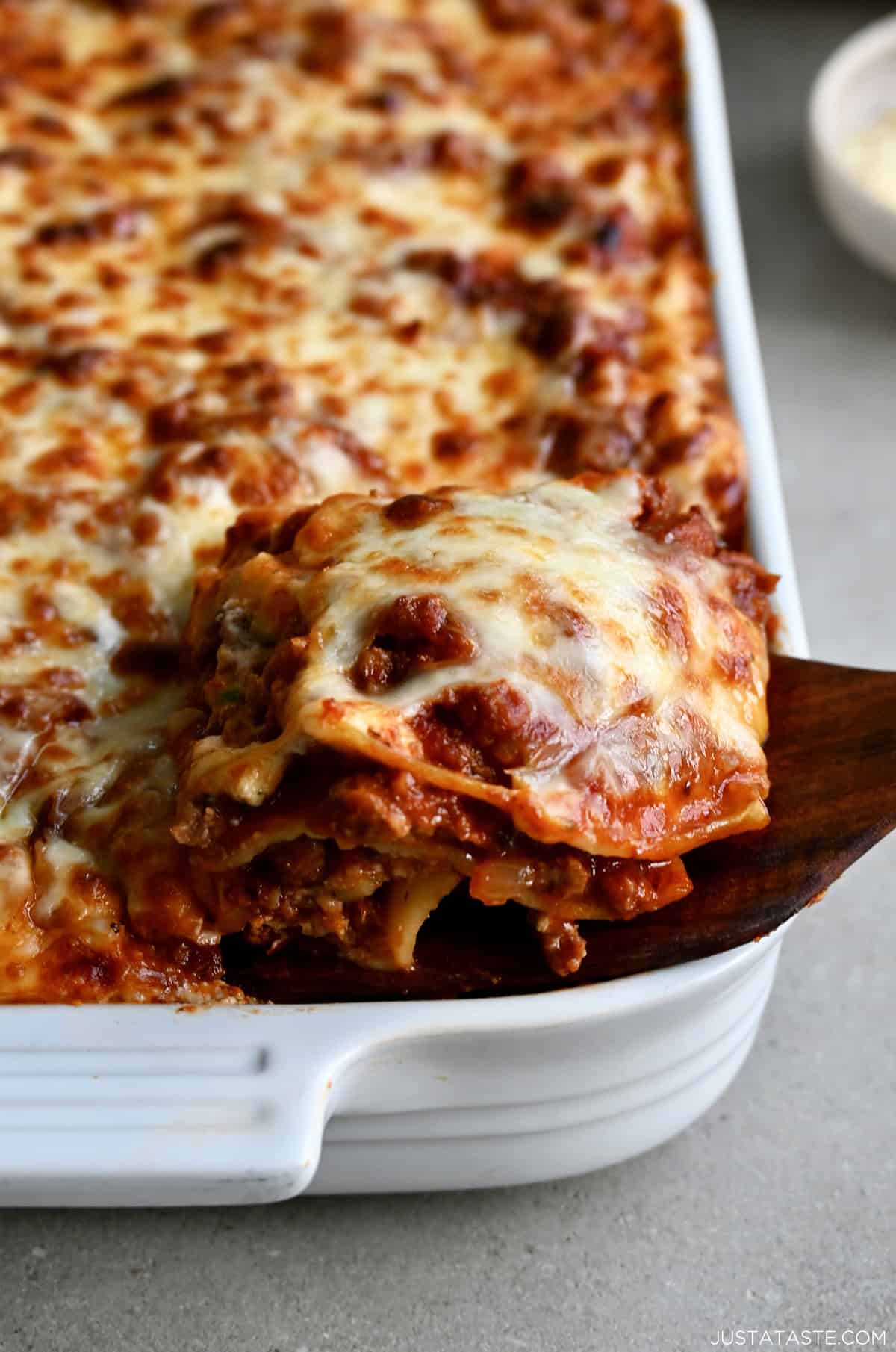 A slice of cottage cheese lasagna being lifted out of a casserole dish.