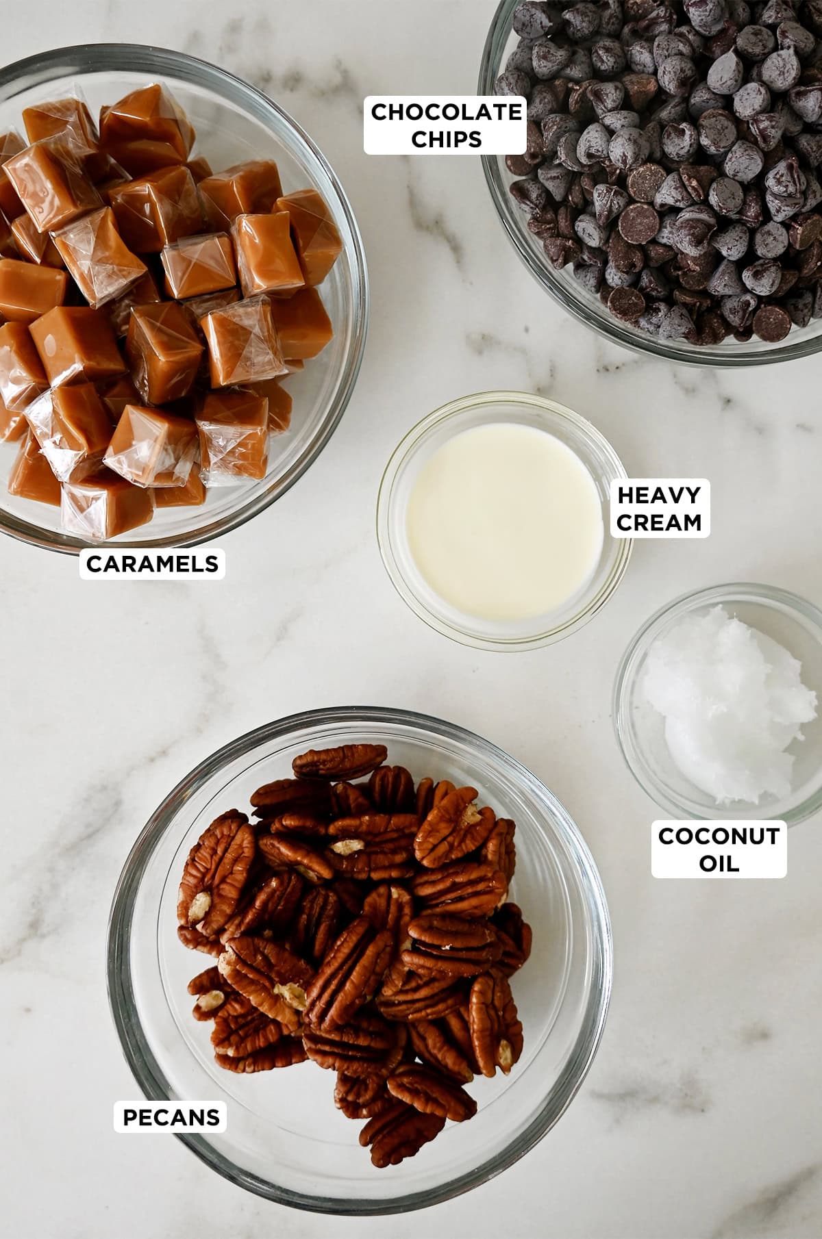 Glass bowls containing the five ingredients needed to make homemade chocolate turtles.